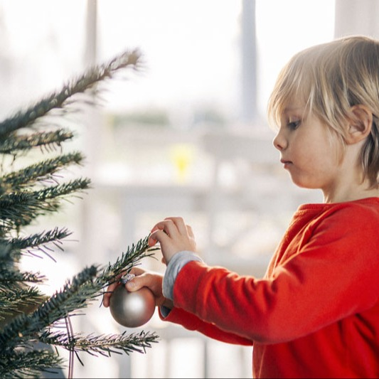 Een man, vrouw en twee kinderen staan bij een kerstboom | Un homme, une femme et deux enfants se tiennent près d'un arbre de Noël