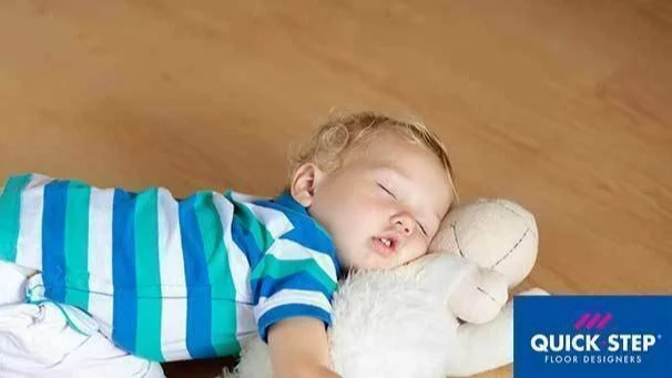 Een kindje ligt met een knuffel op de vloer | Un bébé est allongé sur le sol avec un doudou