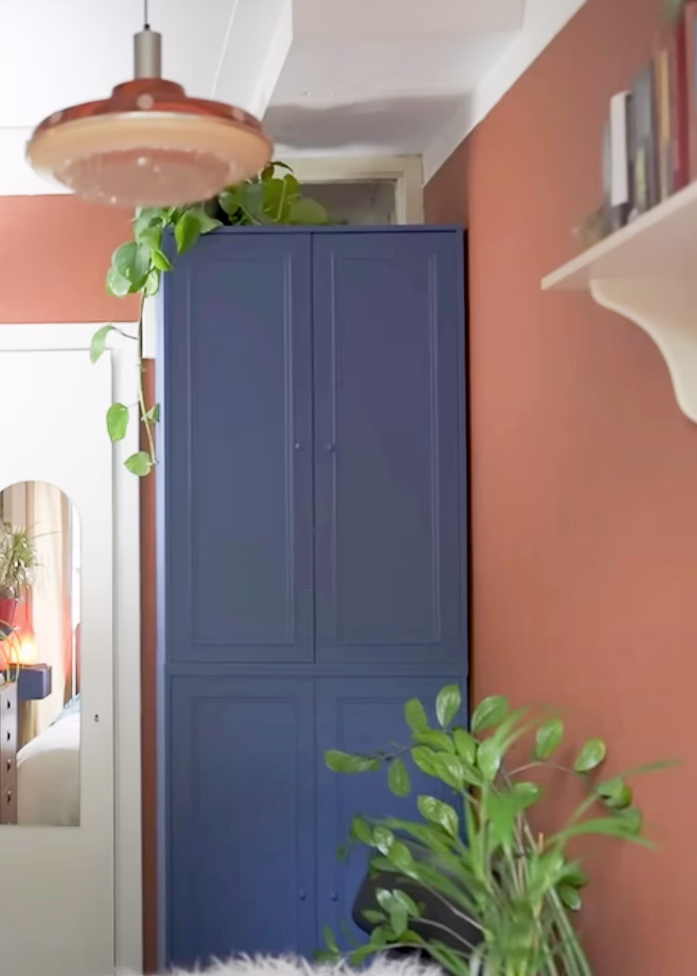 slaapkamer met trendkleuren, geverfde warmroze muur en blauw geschilderde kast
