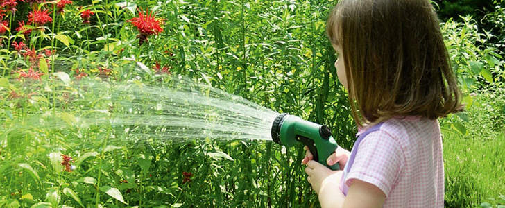 meisje met tuinslang in tuin | fille avec un tuyau d'arrosage dans un jardin