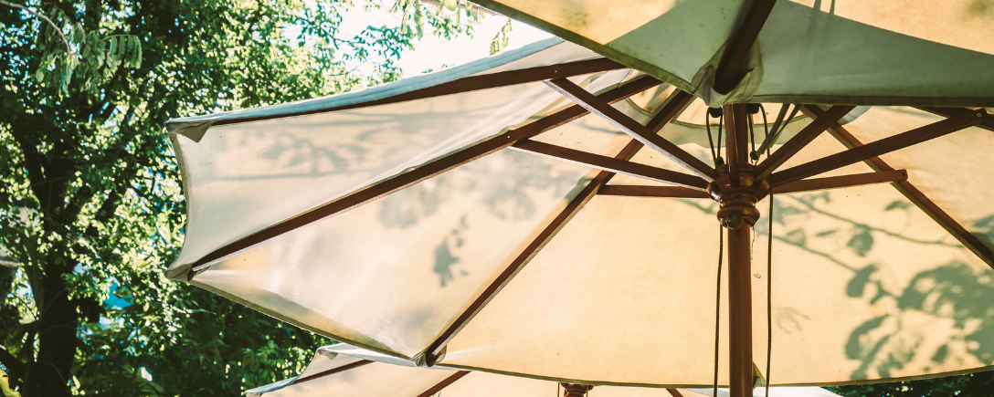 Zonlicht door een crèmekleurige parasol in de tuin | Lumière du soleil à travers un parasol crème dans le jardin