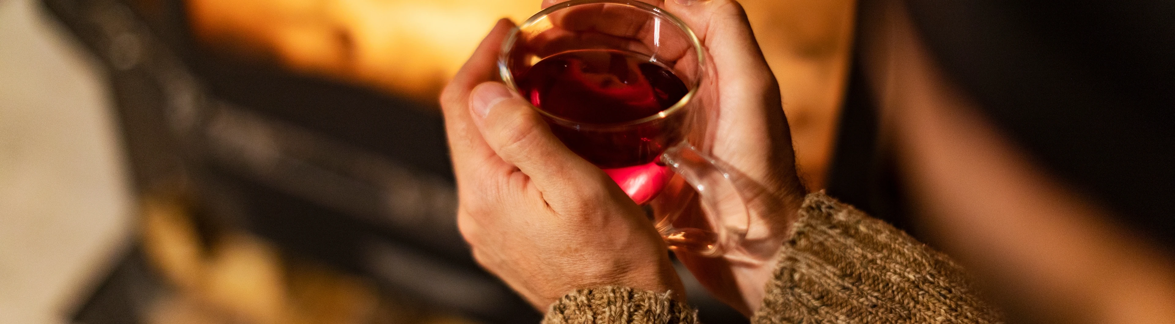 Een persoon met een glas thee voor een open haard | Une personne avec un verre de thé devant une cheminée