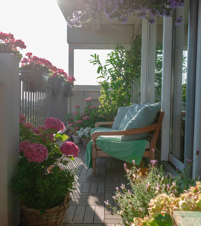 Kleurrijke planten en bloemen en een zetel op een klein balkon | Des plantes et des fleurs colorées et un siège sur un petit balcon