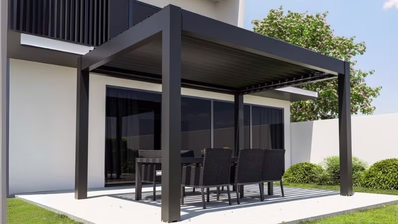 Moderne aluminium pergola op houten terras, aangebouwd aan een witte woning met grote schuiframen | Pergola en aluminium moderne sur terrasse en bois, adossée à une maison blanche avec grandes baies vitrées