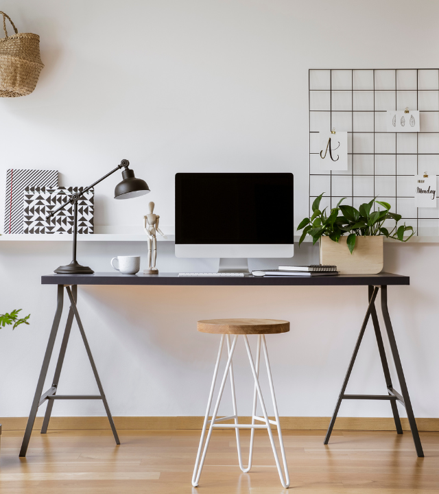 Zwart bureau met een desktop, plant en houten kruk ervoor | Bureau noir avec un bureau, une plante et un tabouret en bois devant lui