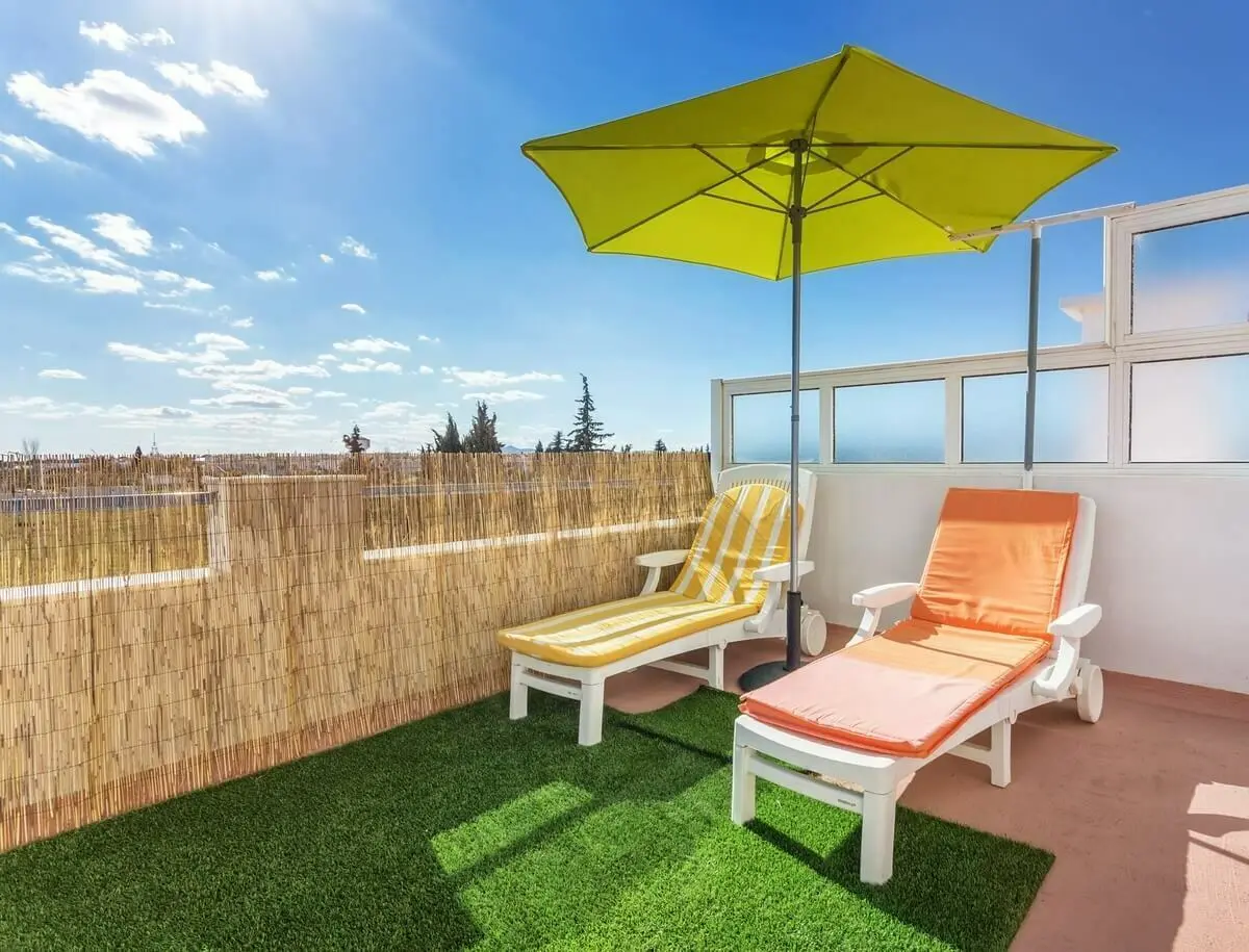 Twee ligstoelen met een parasol ertussen op een dakterras | Deux chaises longues avec un parasol entre elles sur un toit-terrasse