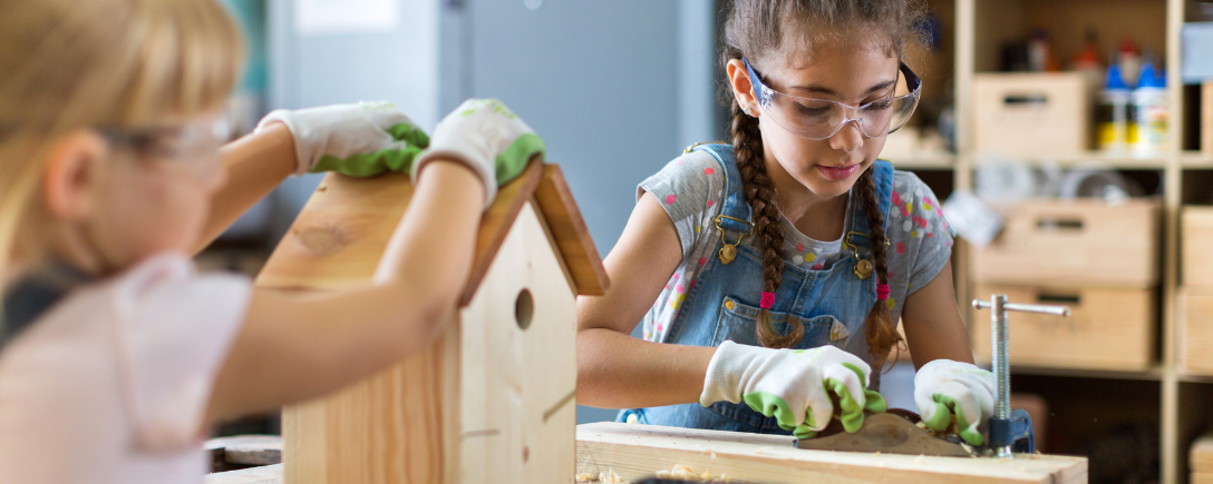 Twee kleine meisjes werken aan een houten vogelhuisje | Deux petites filles travaillant sur un nichoir en bois