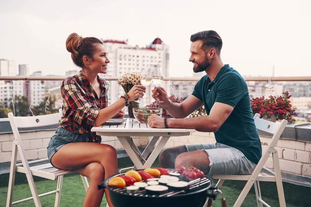 Een man en een vrouw drinken wijn op een Frans tuinsetje op een dakterras | Un homme et une femme boivent du vin dans un jardin français situé sur un toit-terrasse