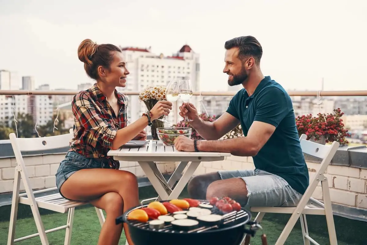 Een man en een vrouw drinken wijn op een Frans tuinsetje op een dakterras | Un homme et une femme boivent du vin dans un jardin français situé sur un toit-terrasse