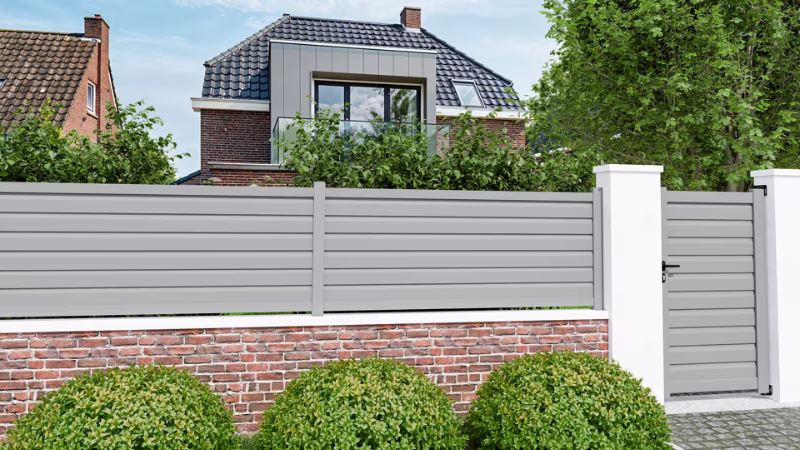 Moderne tuinomheining met horizontale lamellen op een witte betonnen muur. | Clôture de jardin moderne avec lattes horizontales sur un muret en béton blanc.