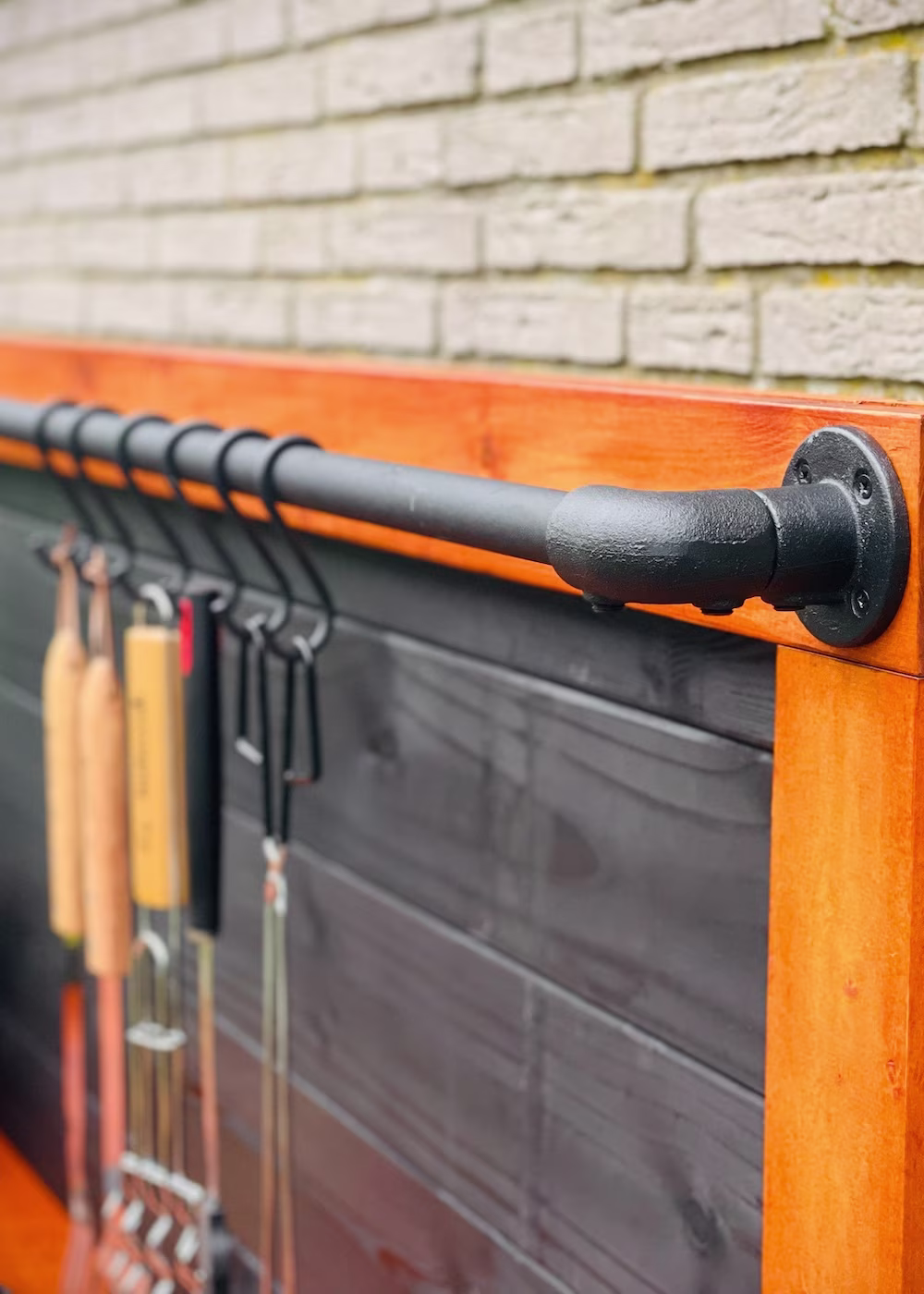 detail DIY buitenkeuken van hout met ophangrek voor bbq gereedschap