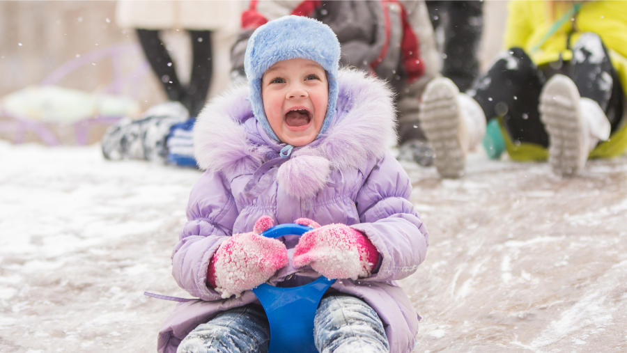 een kind heeft plezier op een slee in de sneeuw | un enfant s'amuse sur une luge dans la neige