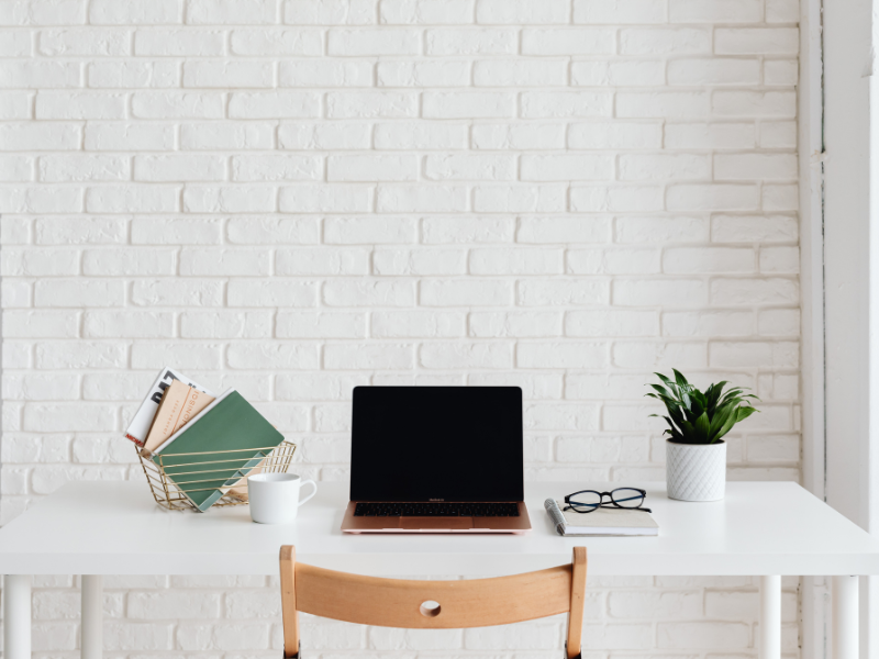 Een wit bureau met een plant, laptop, bril en boeken | Un bureau blanc avec une plante, un ordinateur portable, des lunettes et des livres