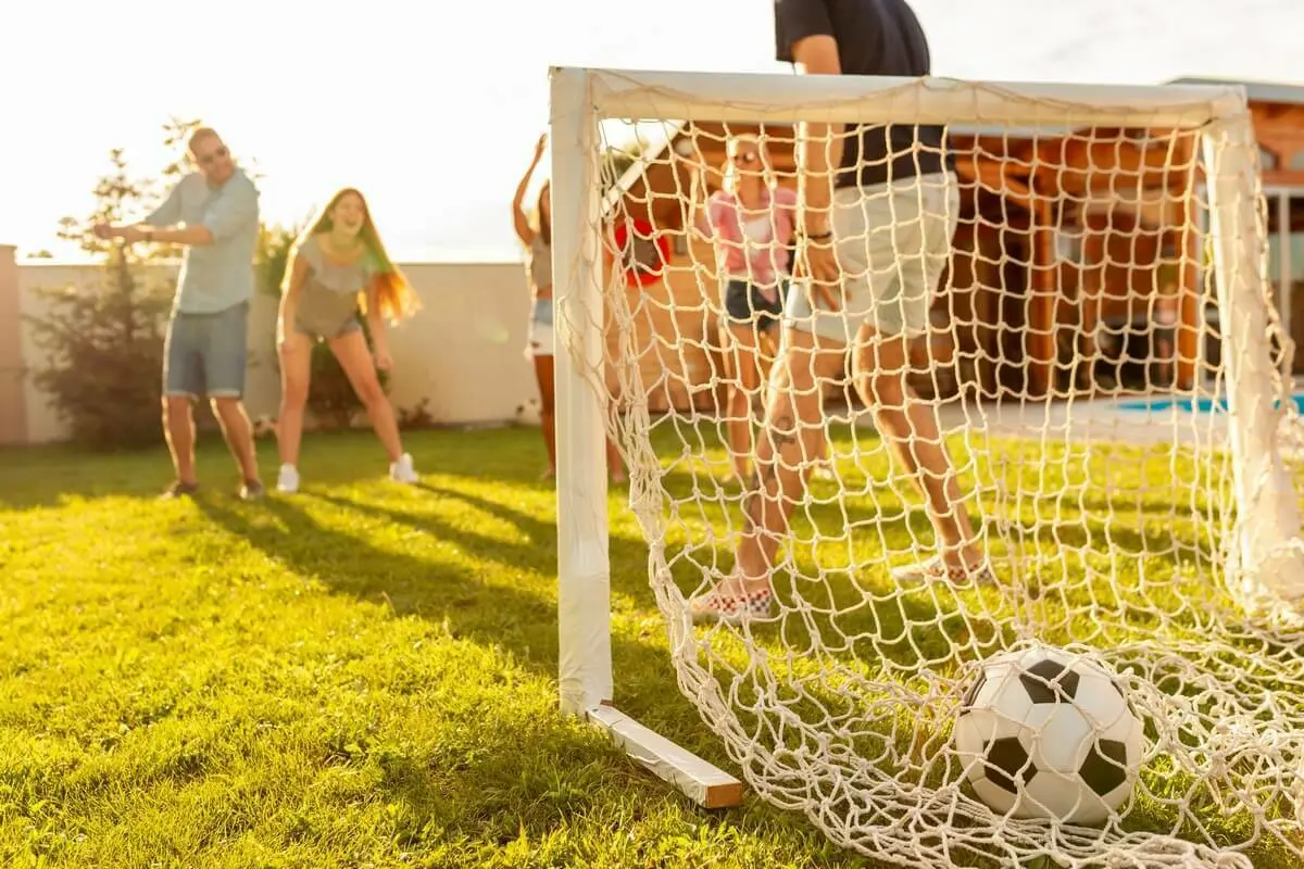 Een voetbalgoal in het gras met voetballende mensen | Un but de football dans l'herbe avec des gens qui jouent au football