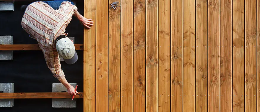 Een man met een potlood in zijn hand staat voor de houten vloer | Un homme avec un crayon à la main se tient devant le plancher en bois