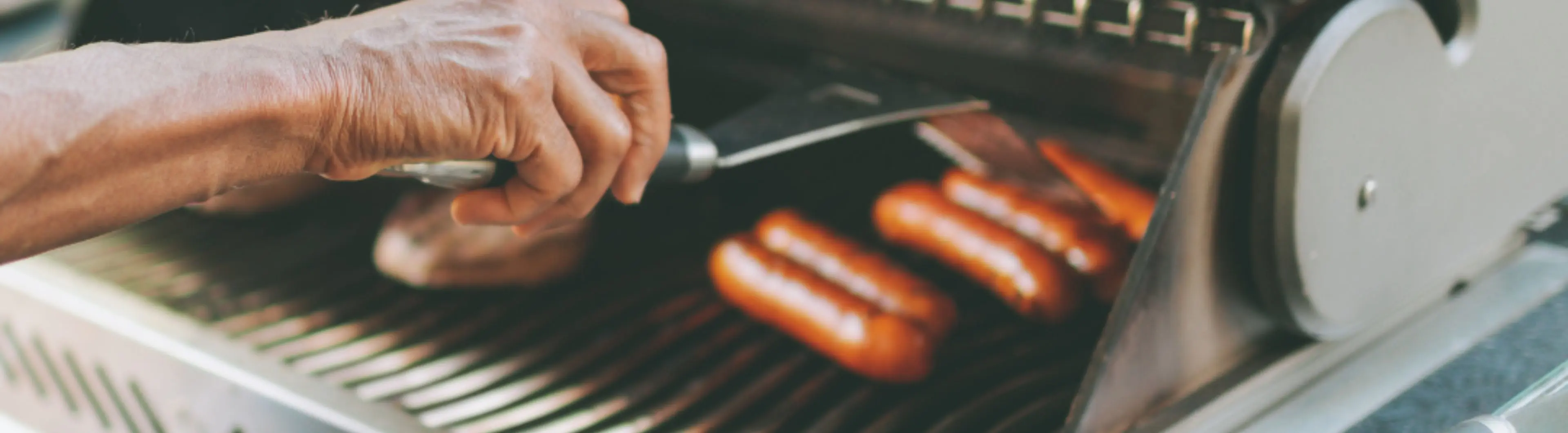 iemand die hotdogs grilt op een grill | personne qui fait griller des hot-dogs sur un gril