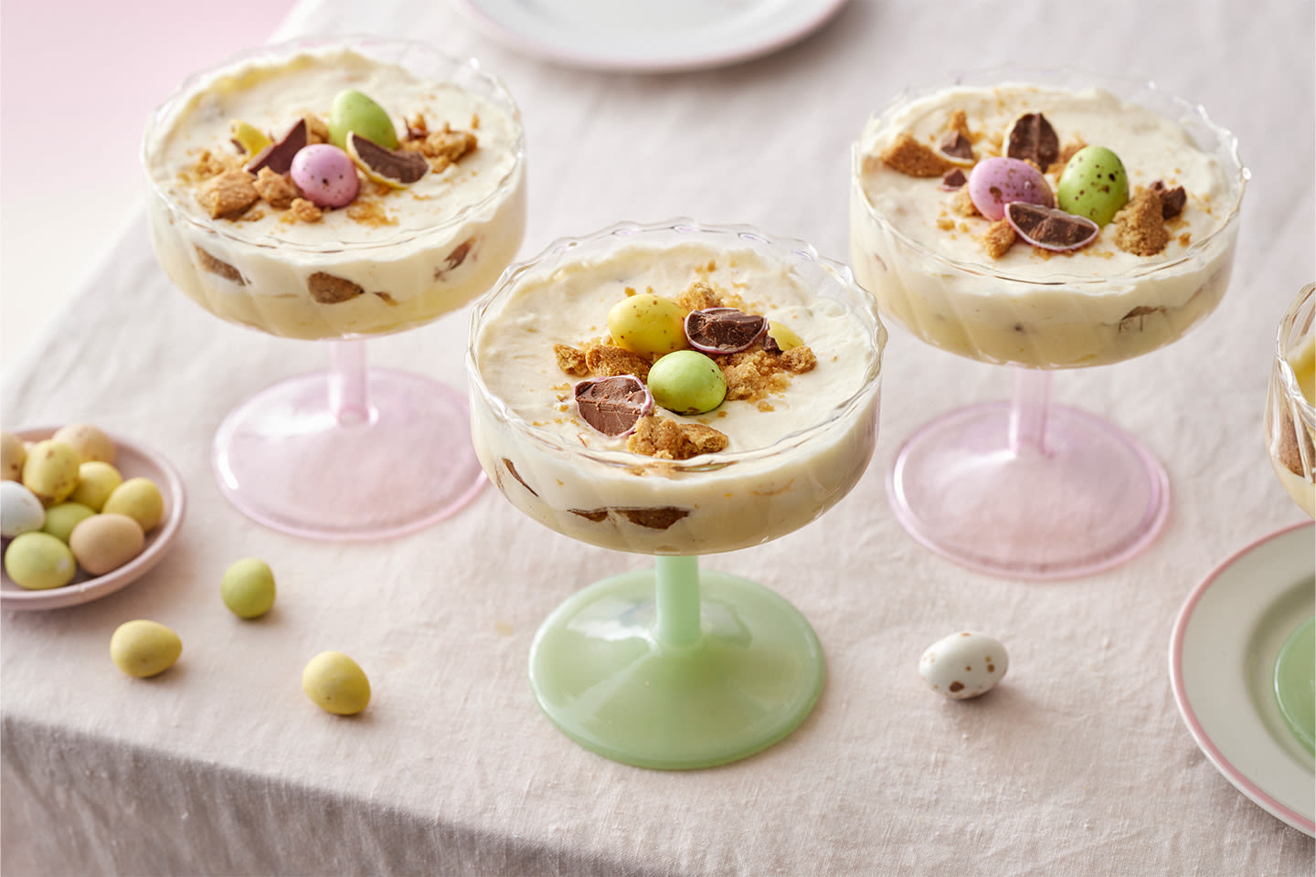 Herkullisia pääsiäisjälkiruokia laseissa, koristeltu suklaapalasilla ja värikkäillä minipääsiäismunilla.