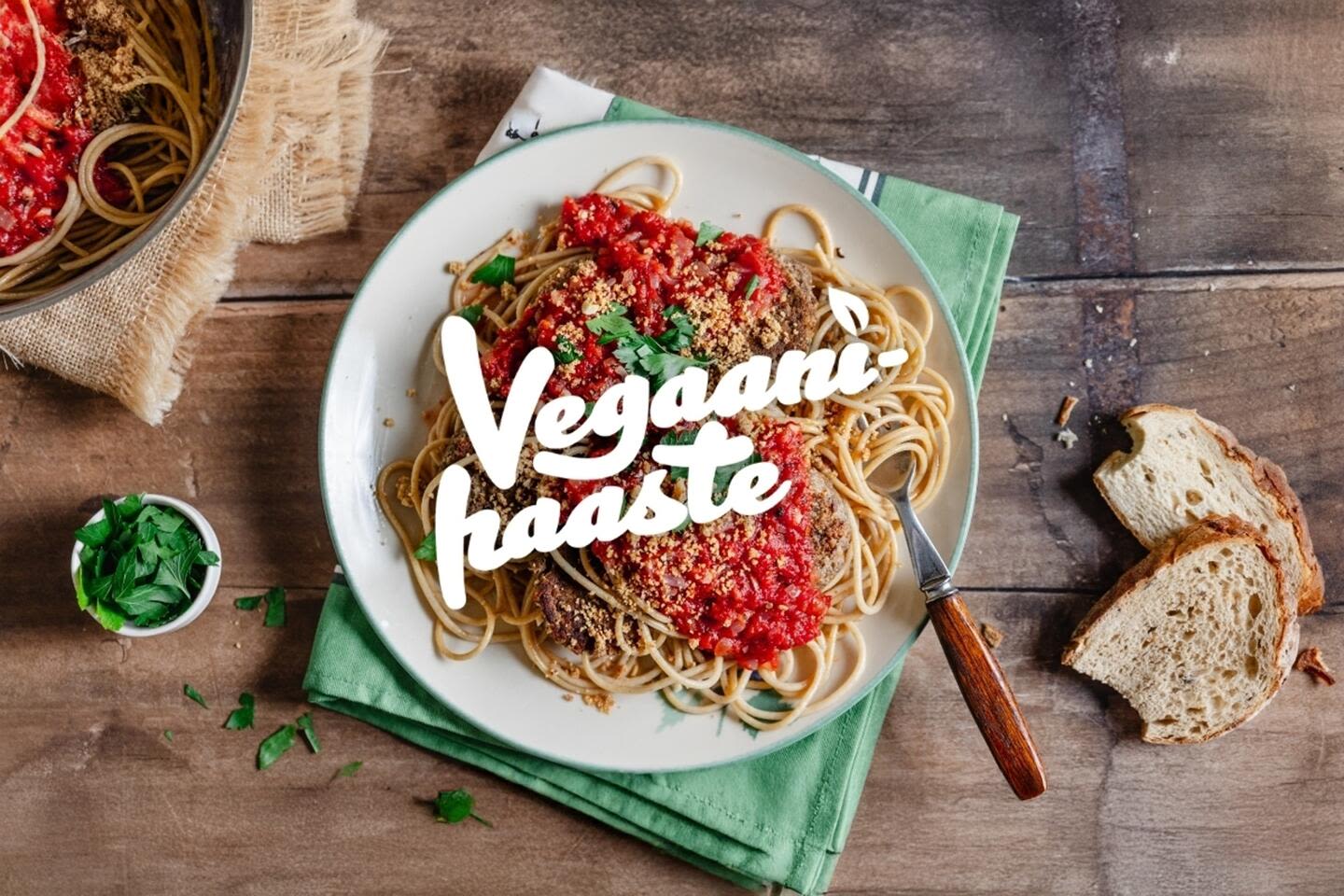 Herkullinen vegaaninen spagetti tomaattikastikkeella ja yrteillä koristeltuna, "Vegaanihaaste" -tekstillä, leipäviipaleita vieressä.