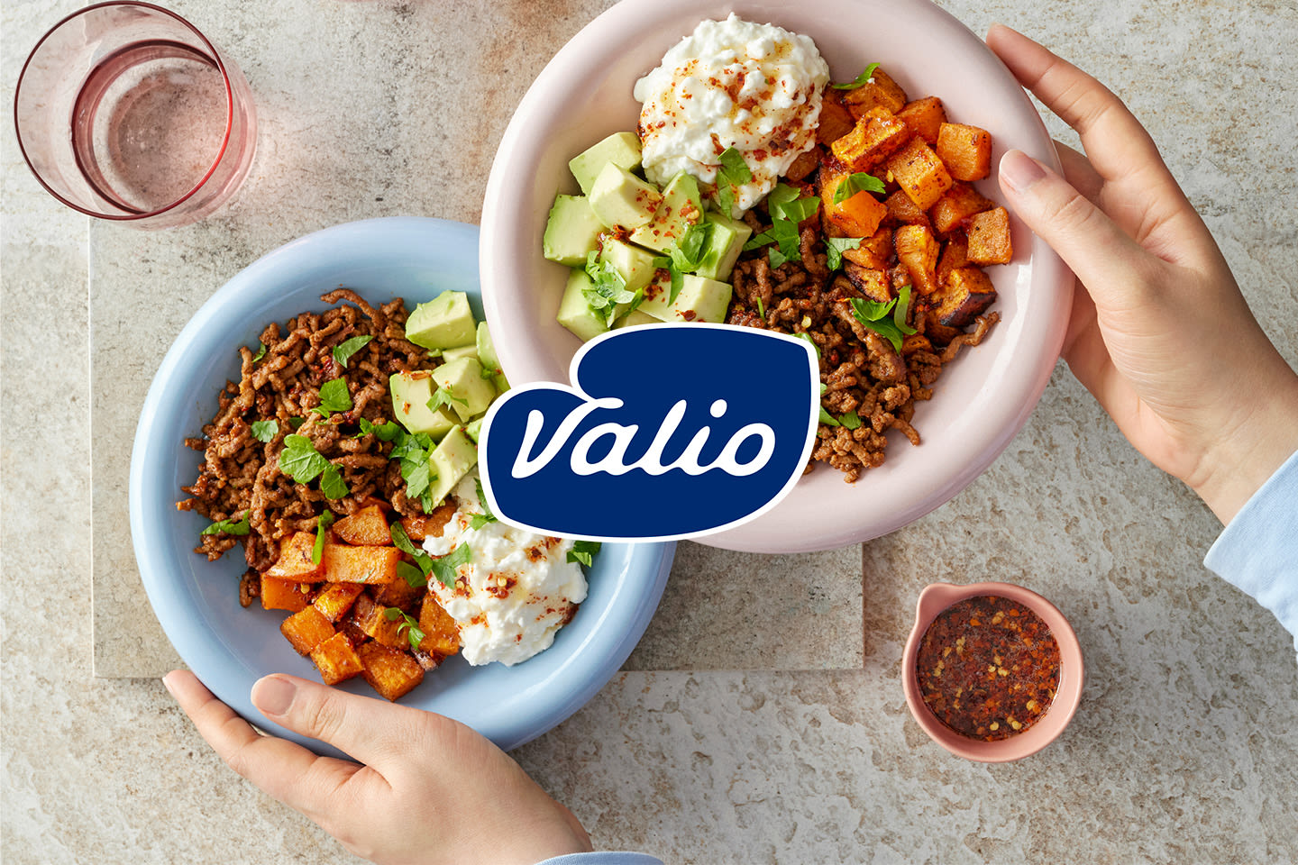 Kaksi värikästä kulhoa täynnä maukasta ruokaa: jauhelihaa, bataattikuutioita, avokadoa ja raejuustoa, Valion logo keskellä.