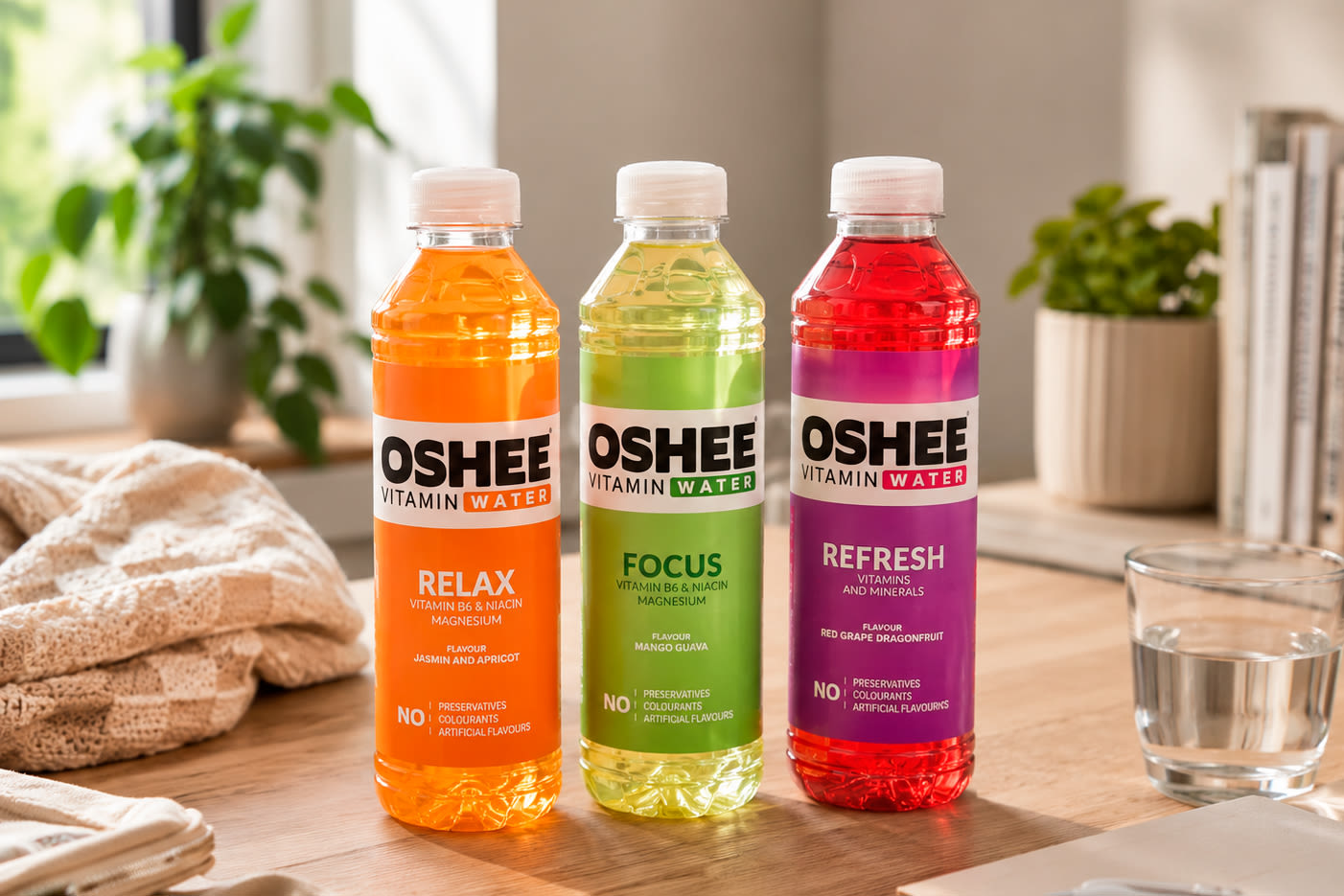 Kolme Oshee Vitamin Water -pulloa pöydällä: oranssi Relax, vihreä Focus ja punainen Refresh.
