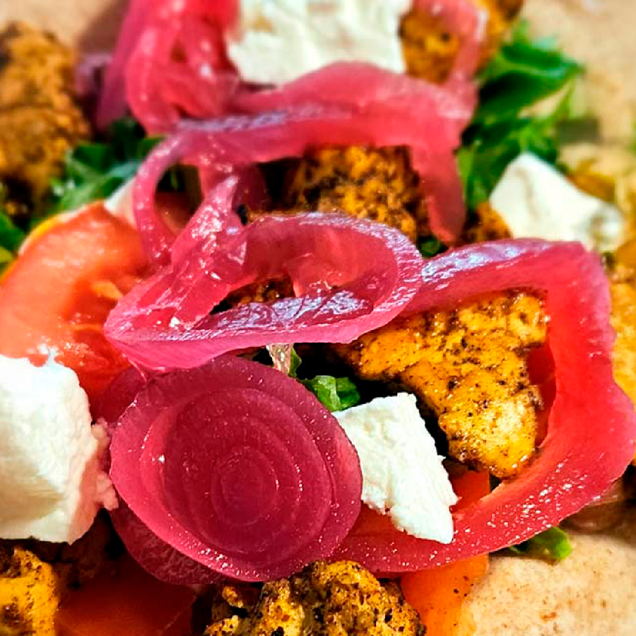 Värikäs salaatti, jossa punajuurta, valkoista juustoa ja mausteista kanaa vihreillä yrteillä koristeltuna.