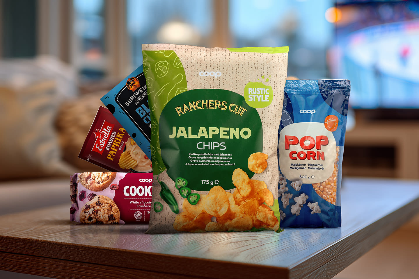 Herkullinen naposteltavien kokoelma pöydällä: jalapeno-sipsejä, popcornia, keksejä ja muita herkkuja.