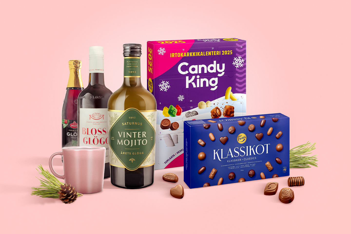 Jouluisia herkkuja: glögipulloja, Candy King -joulukalenteri, suklaakonvehteja ja muki vaaleanpunaisella taustalla.