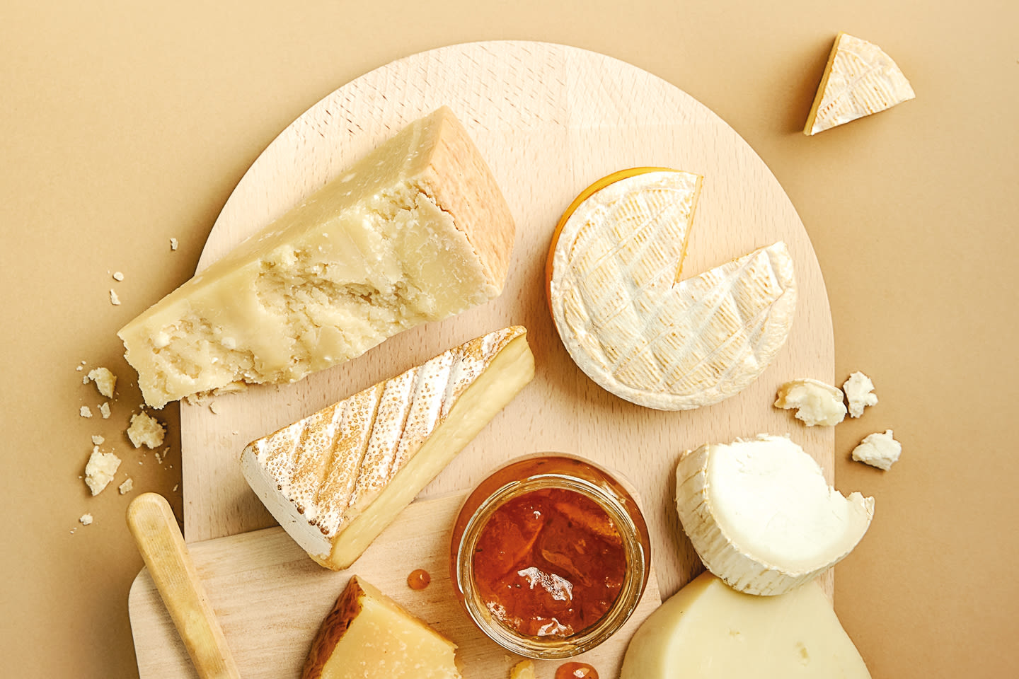 Herkullinen juustolautanen puisella alustalla, jossa erilaisia juustoja ja hunajaa pienessä lasipurkissa.
