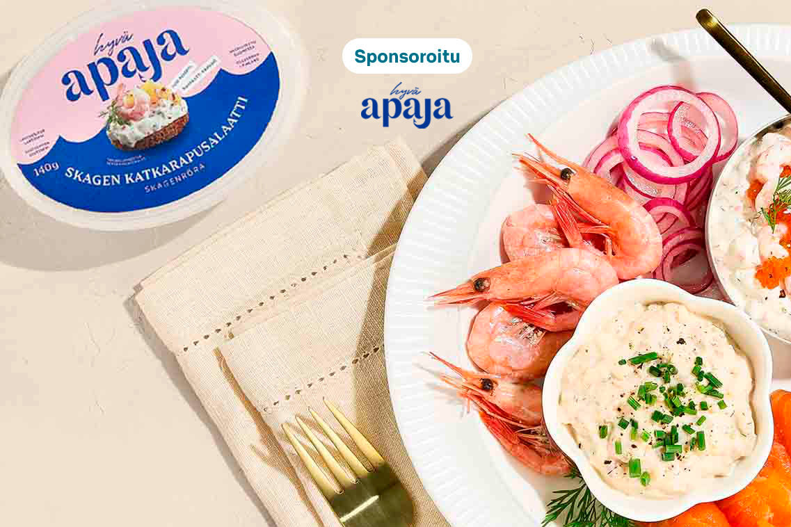 Valkoinen lautanen täynnä mereneläviä: katkarapuja, lohta, punasipulia, ruisleipää ja kahta eri moussesalaattia. Vieressä Apaja-katkarapusalaattipakkaus. Merkintä "Sponsoroitu".