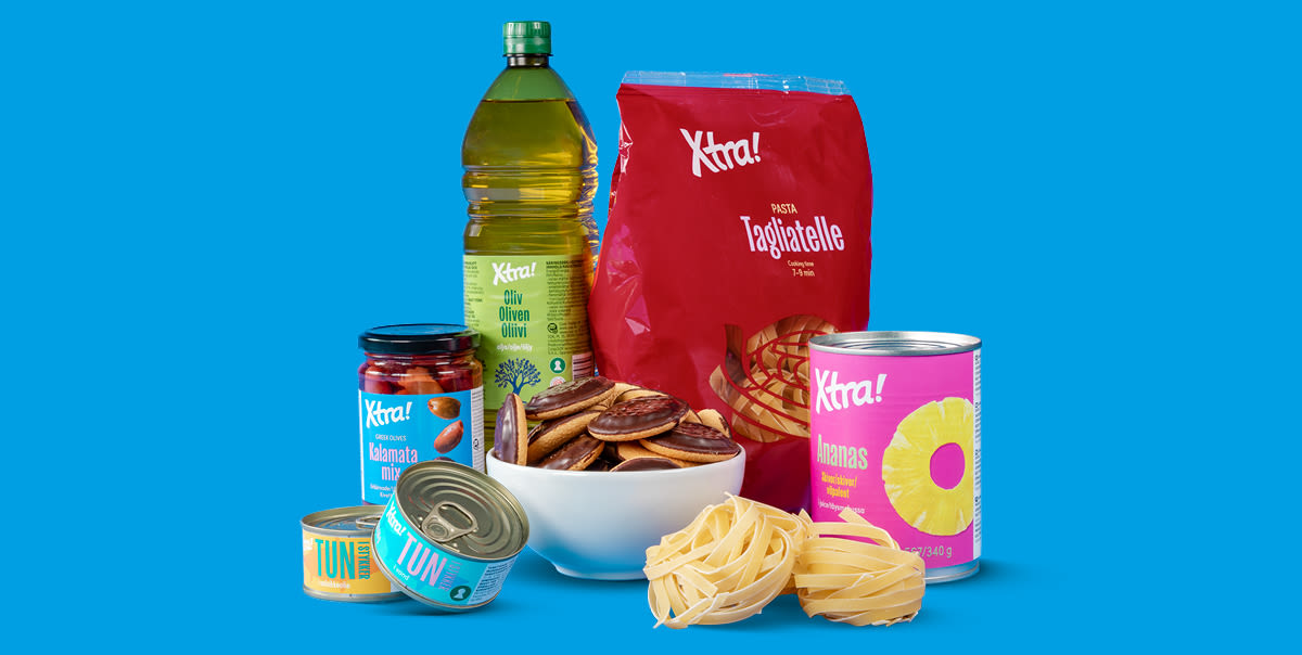 Xtra-tuotteita sinisellä taustalla: oliiviöljy, tagliatelle-pasta, tonnikalapurkit, kalamata-oliivit, ananaspurkki ja suklaakeksejä.