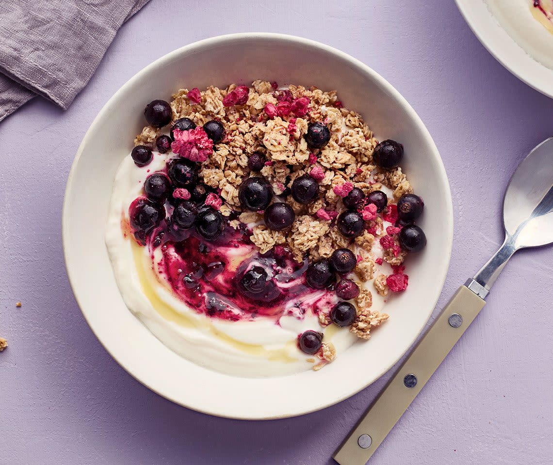 Jogurttia, mustaherukoita, mysliä ja hunajaa kupissa