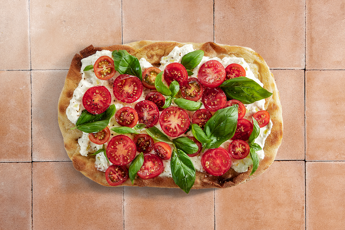 Herkullinen italialainen pinsa, jossa rapea pohja, juustoa, tuoreita kirsikkatomaatteja ja basilikanlehtiä.