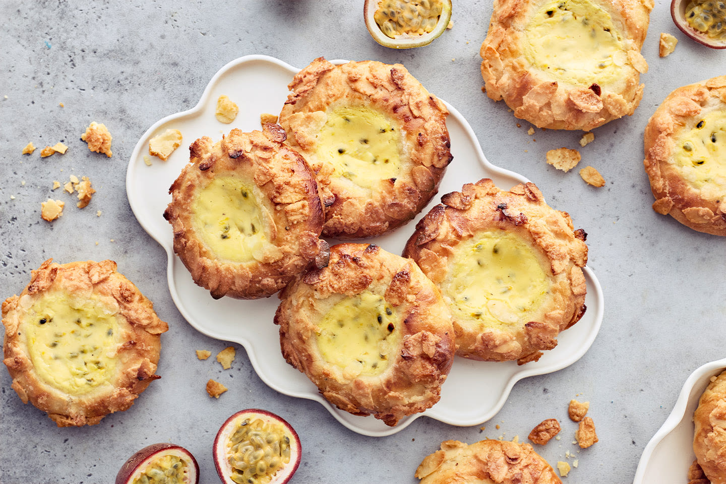 Rapeareunaiset toscapullat valkoisella tarjoilulautasella, ympärillä tuoreita passionhedelmiä ja muruja.