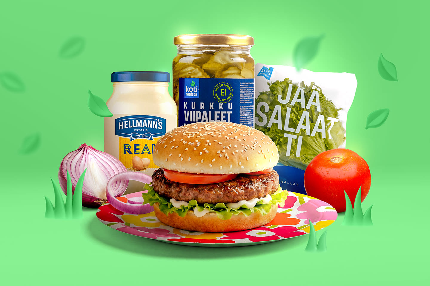Tuore hampurilainen kukallisella lautasella, ympärillä Hellmann's-majoneesi, Kotimaista-kurkkuviipaleet, jäävuorisalaatti, tomaatti ja punasipuli.