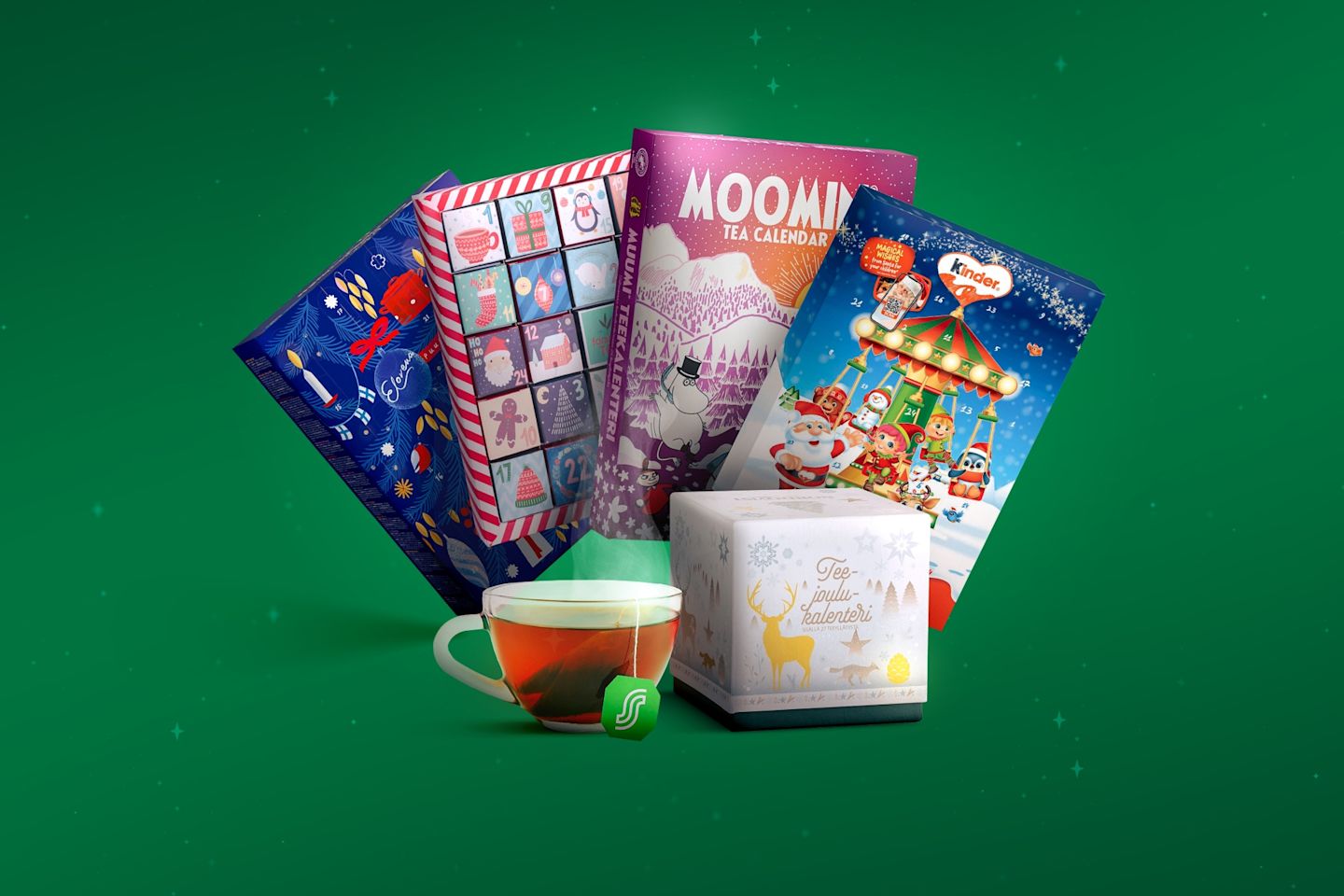 Jouluisia adventtikalentereita, kuten Muumi-teekalenteri ja Kinder, sekä teekuppi vihreällä taustalla.