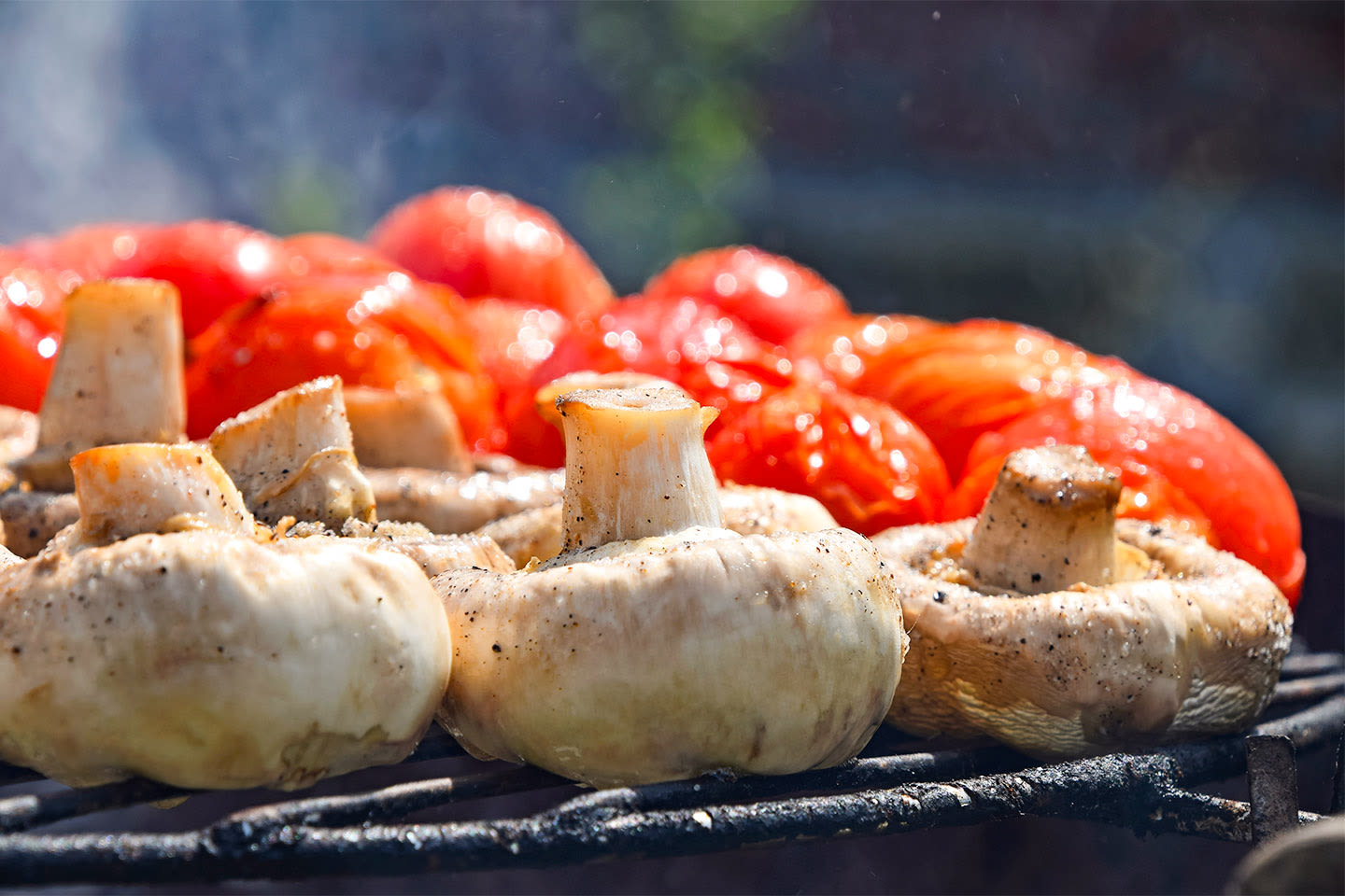 Mehukkaita herkkusieniä ja tomaatteja grillautumassa, täydelliset ainekset kesäiseen ruoanlaittoon.