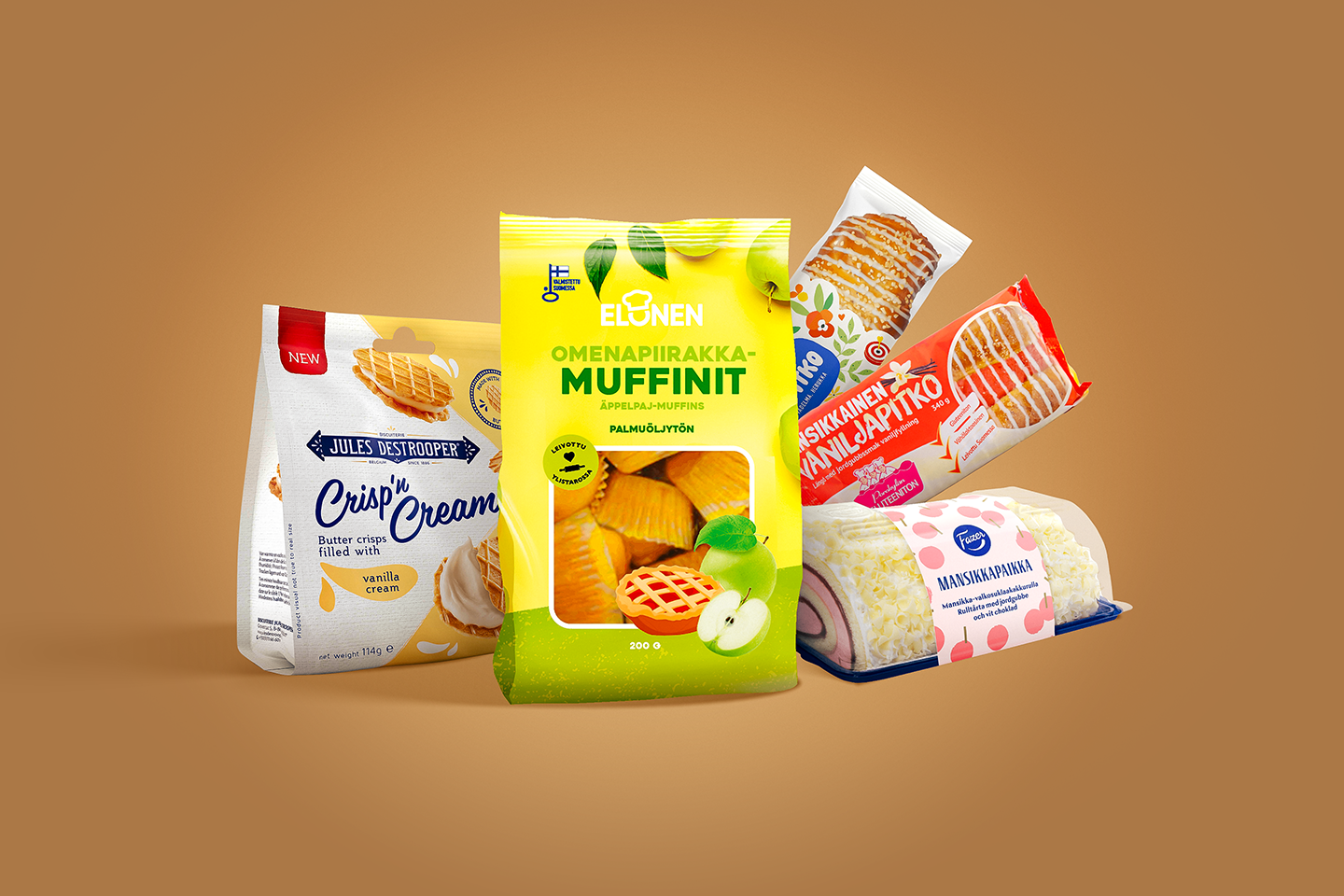Elonen omenapiirakkamuffinit, Fazer Mansikkapaikka -torttu, Jules Destrooper Crisp 'n Cream, Mansikkainen vaniljapitko, Trube Kesäpitko ruskealla taustalla. 