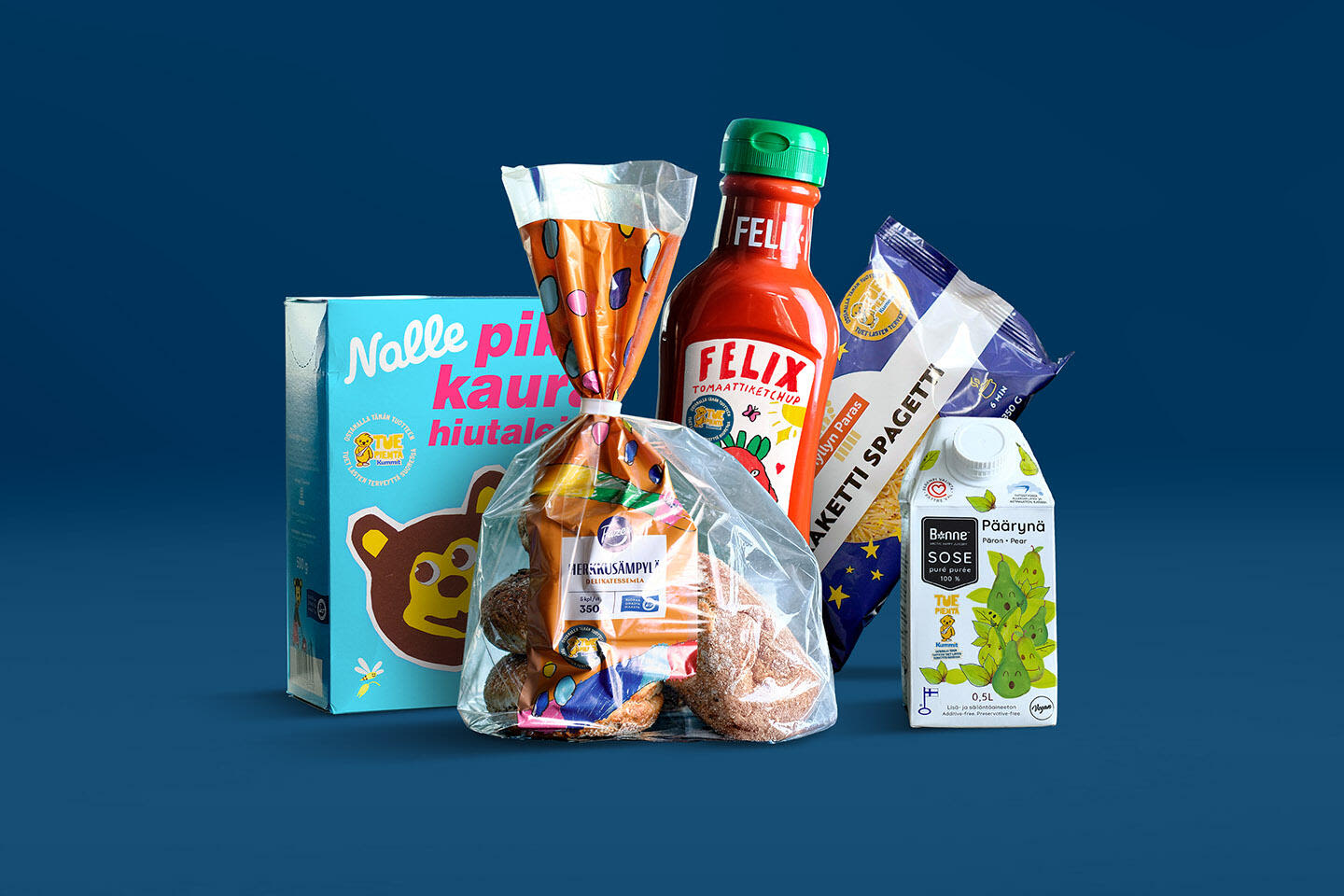 Sinisellä taustalla joukko Tue pientä -kampanjan ruokatuotteita, joilla on lasten suunnittelema design: Nalle-kaurahiutaleet, Felix-ketsuppi, Myllyn paras raketti spagetti, sämpyläpussi ja Bonne-päärynäsose.