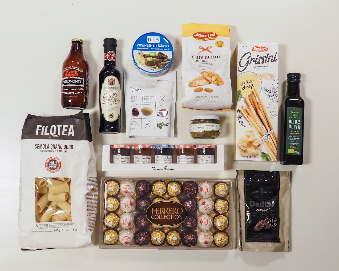Italialaisia herkkuja sisältävä kokoelma: pastaa, oliiviöljyä, balsamicoa, suklaata ja muita laadukkaita ruokatuotteita siististi aseteltuna.