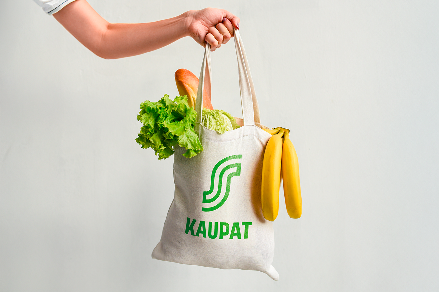 Henkilö pitää kädessään S-kaupat-kangaskassia, joka on täytetty ruokatuotteilla.