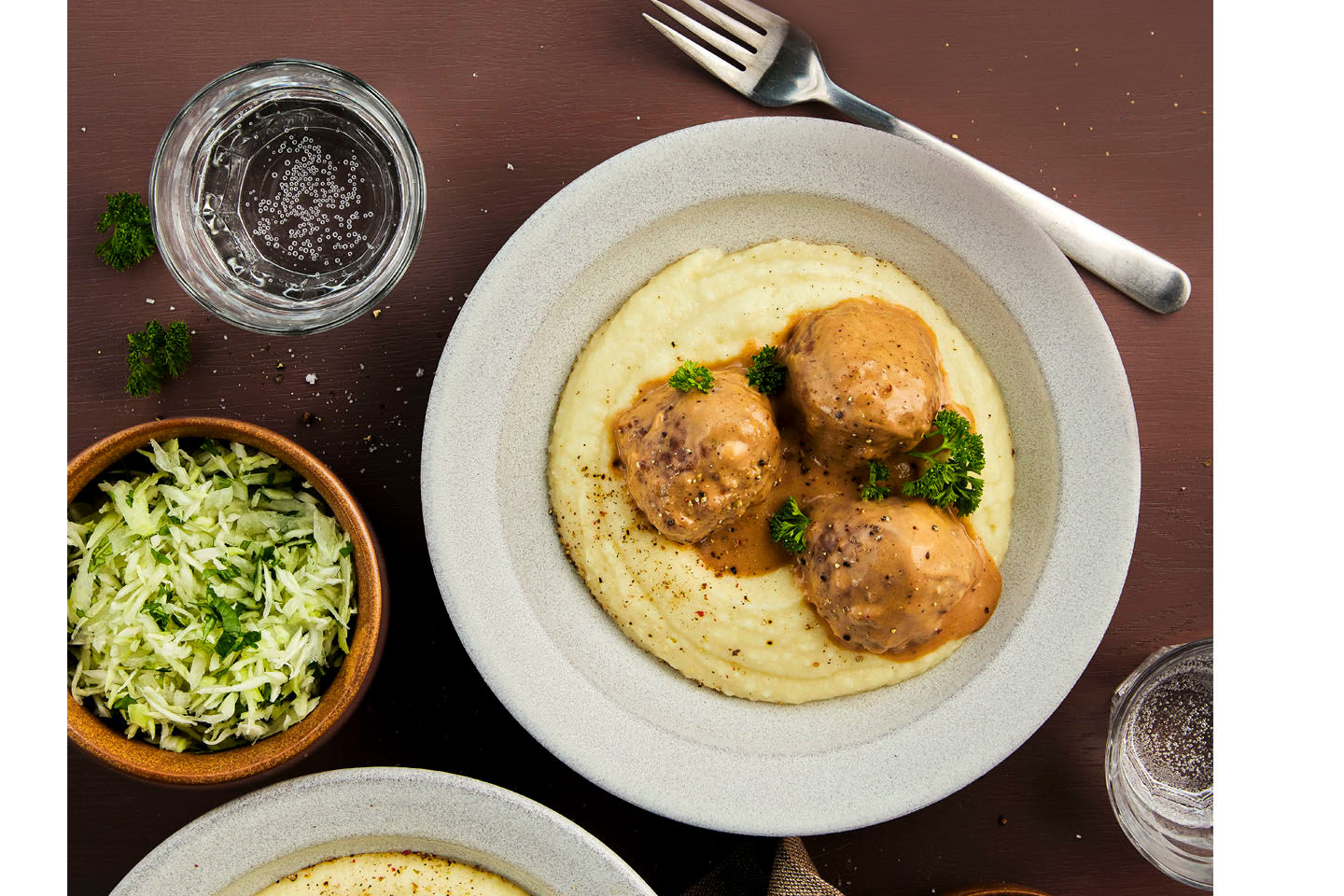 Lihapullia ja perunasosetta lautasilla. Vieressä vesilasi, haarukka ja raastesalaattia.