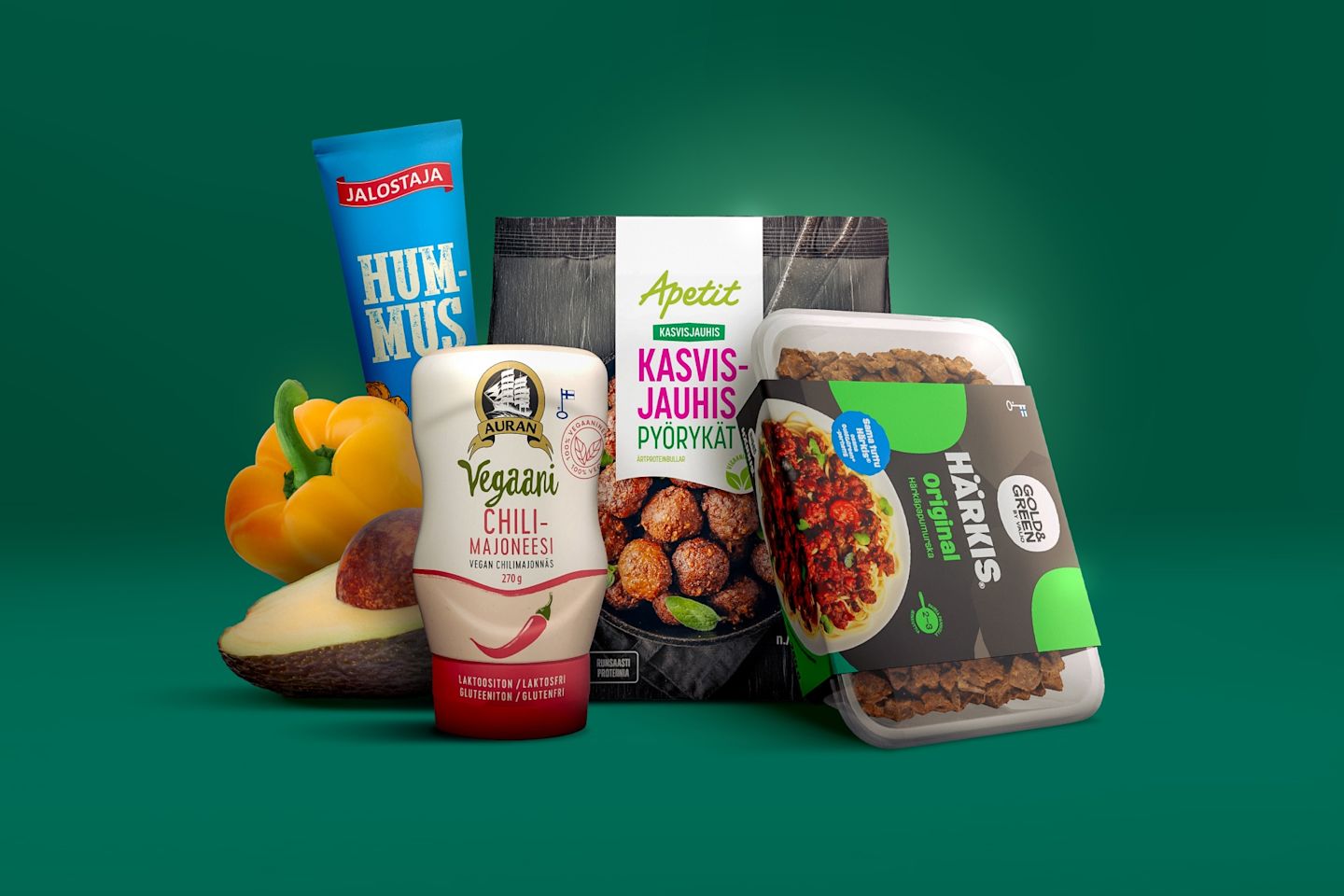 Vihreällä taustalla kasvispohjaisia tuotteita: Jalostajan hummus, Auran vegaani chilimajoneesi, Apetitin kasvisjauhispyörykät ja Gold&Greenin Härkis.
