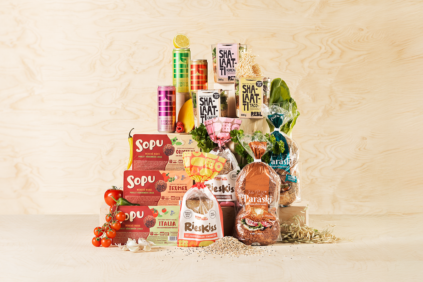 Suomalainen menestysresepti -kisan finalisteja, kuten Sopu-kasvispihvejä, Shalaatti-aterioita, juomia ja leipää puisella taustalla.