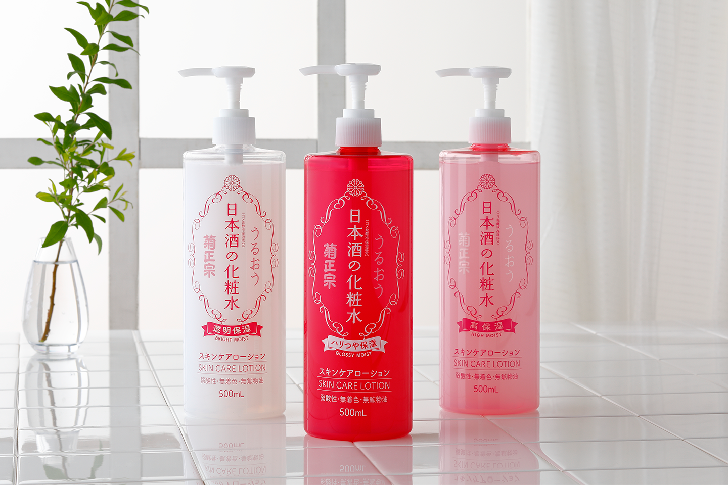 Kolme japanilaista ihonhoitotuotetta valkoisessa, punaisessa ja vaaleanpunaisessa pullossa valoisalla ikkunalaudalla viherkasvien vieressä.