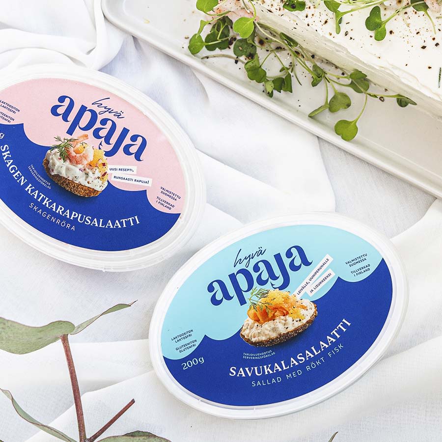 Kaksi Hyvä Apaja -salaattipurkkia vierekkäin: vaaleanpunainen skagen-katkarapusalaatti ja sininen savukalasalaatti.