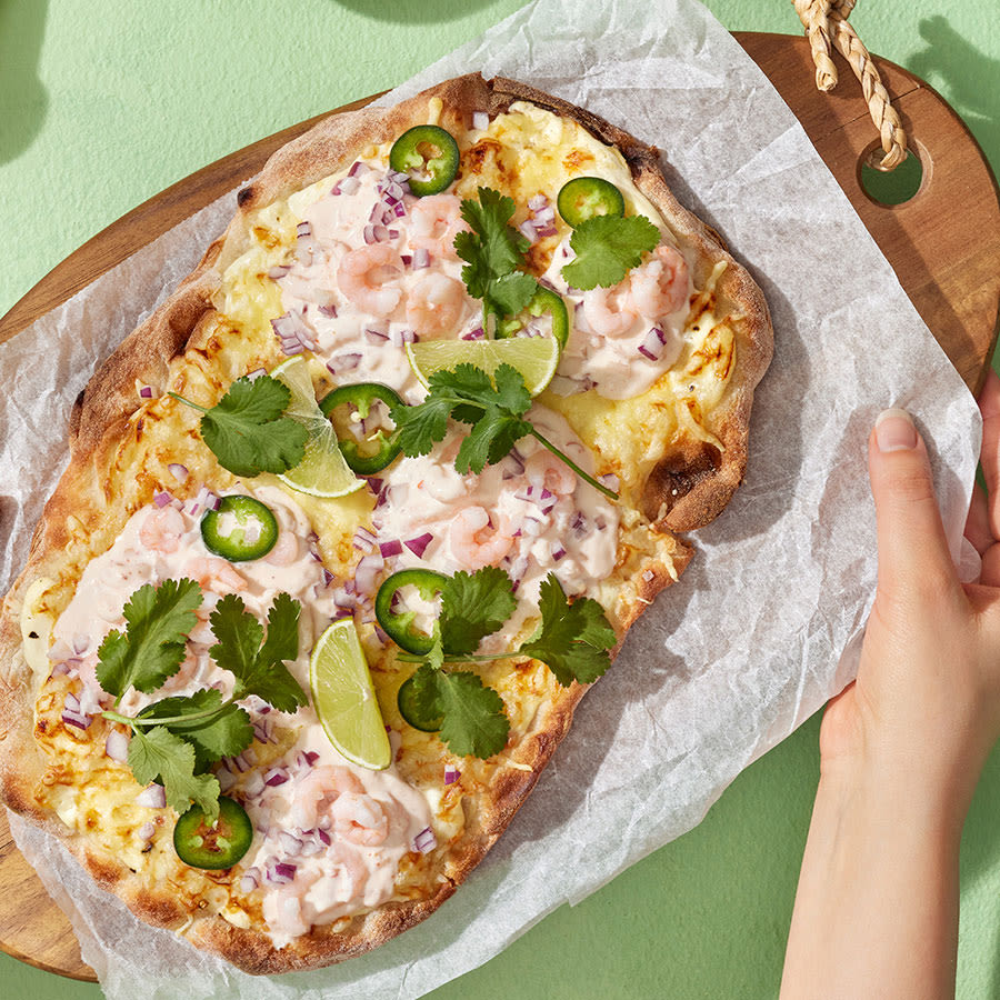 Pinsa katkaravuilla, jalapenoviipaleilla, korianterilla ja limetillä puisella leikkuulaudalla