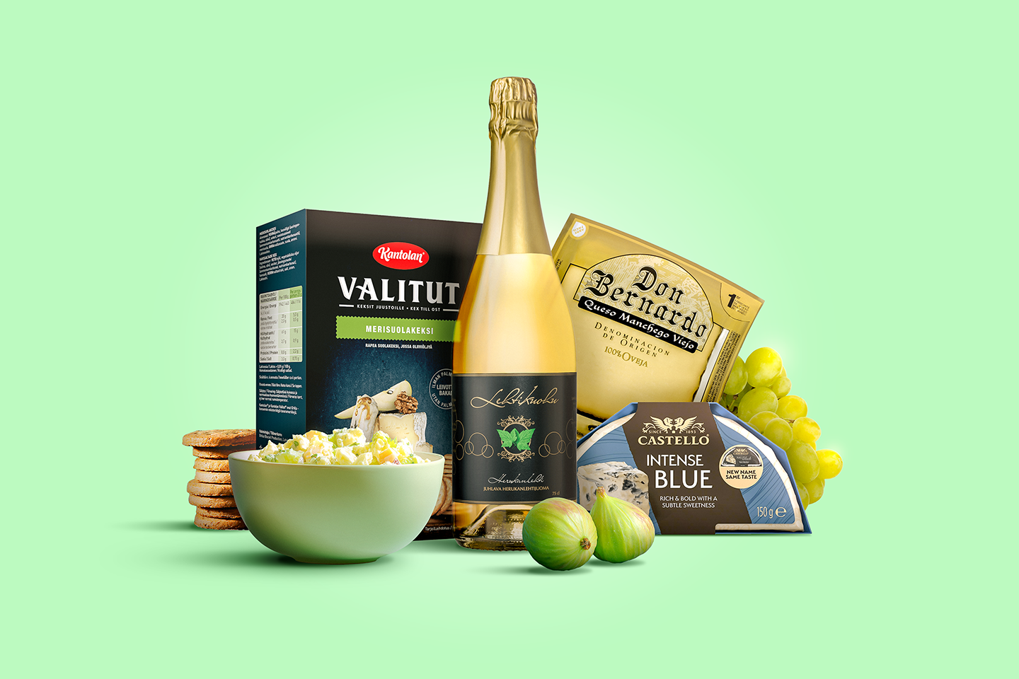 Herkullinen juustolautanen, jossa samppanjapullo, sinihomejuustoa, keksejä, viinirypäleitä ja tuorejuustoa vaaleanvihreällä taustalla.