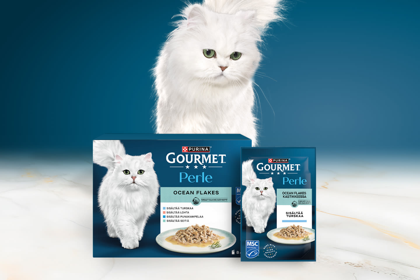 Pehmeäturkkinen valkoinen kissa Purina Gourmet Perle Ocean Flakes -kissanruokapakkausten takana sinistä taustaa vasten.