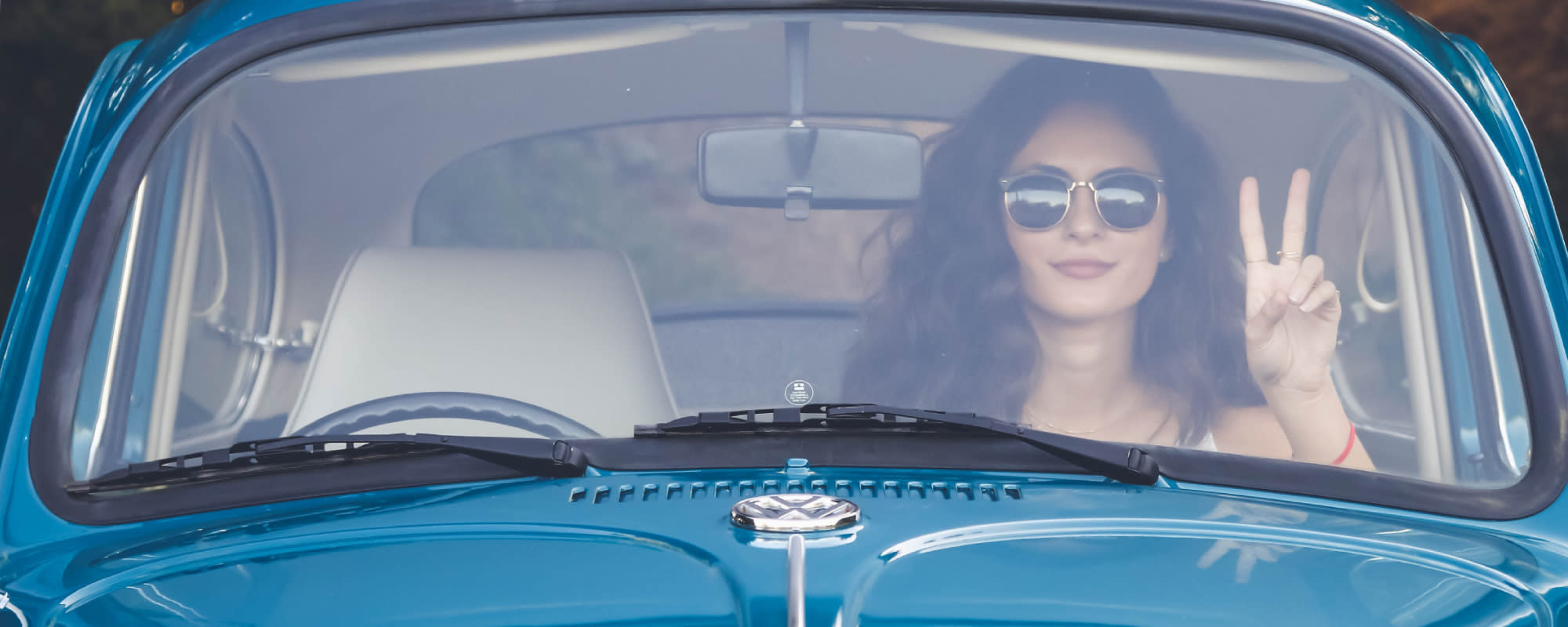 Hero-woman-in-car-blue-v-sign