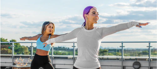 2 women doing yoga on rooftop